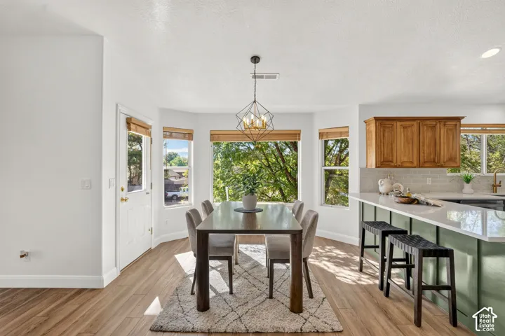 Wood-finish flooring throughout, a bay window with natural light, and a geometric chandelier