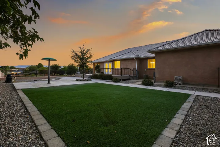 Expansive backyard featuring artificial turf, concrete pathways, and a gravel perimeter