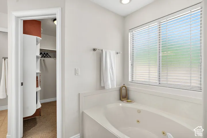 Jetted soaking tub with a large window and horizontal blinds