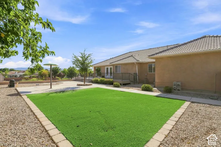 Expansive backyard featuring artificial turf, a concrete patio, and gravel landscaping
