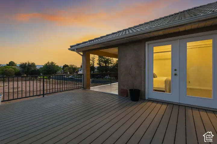 Expansive outdoor deck featuring composite decking, black metal railings, and dual glass-paneled doors