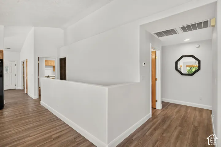 Vaulted ceiling, wood-finish flooring, white walls, wood panel interior doors, recessed lighting