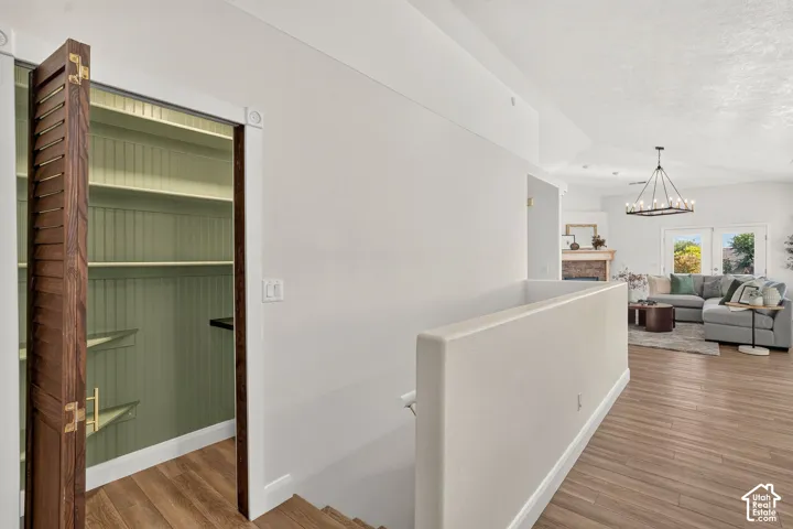 Wood-finish flooring throughout, bright white walls, built-in shelving, and a decorative chandelier
