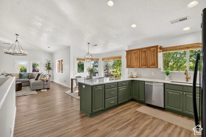 Kitchen featuring wood-finish flooring, two-tone cabinetry, stainless steel dishwasher, and a center island with countertop seating