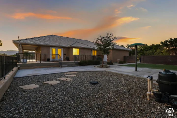Tile-roof residence with a covered patio, featuring a railing and steps to the outdoor area