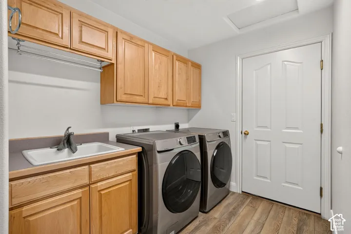 Laundry area featuring wood-finish flooring, built-in cabinetry, a utility sink, and a clothes hanging rod