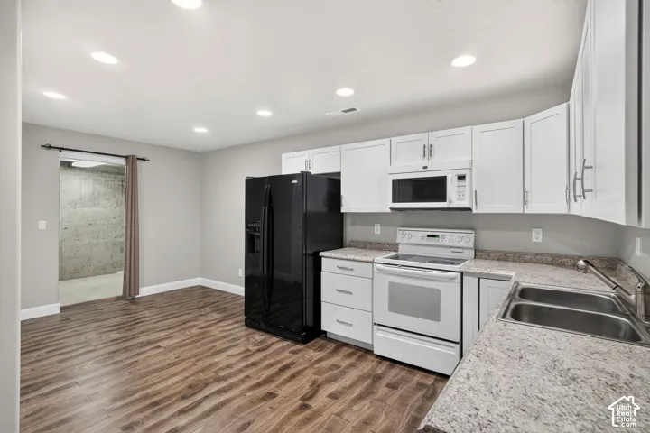 Kitchen featuring wood-finish flooring, white cabinetry with silver-tone hardware, a double basin stainless steel sink, and light-toned countertops