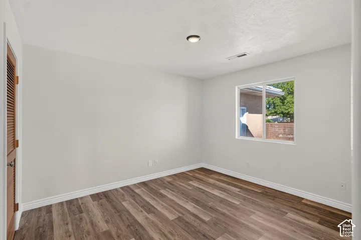 Wood-finish flooring, white trim, recessed lighting, and a louvered bi-fold door