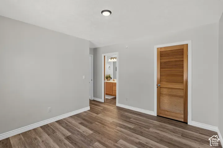 Wood-finish flooring throughout, white baseboards, and a contemporary flush-mount ceiling light