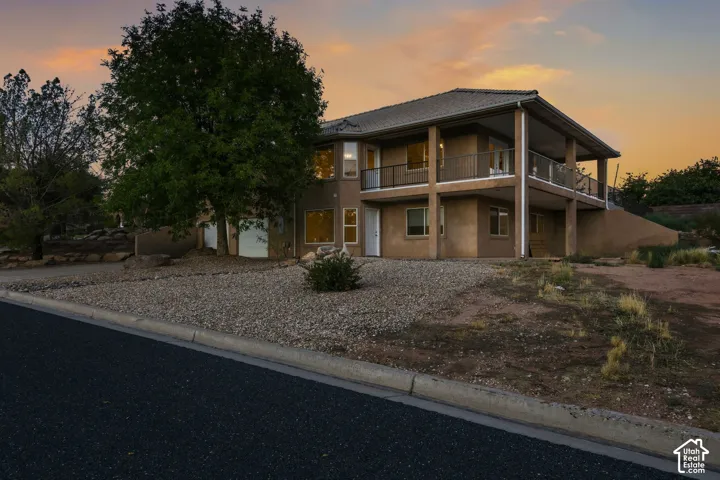 Two-story stucco exterior with a covered upper-level balcony, lower-level covered patio, and attached two-car garage