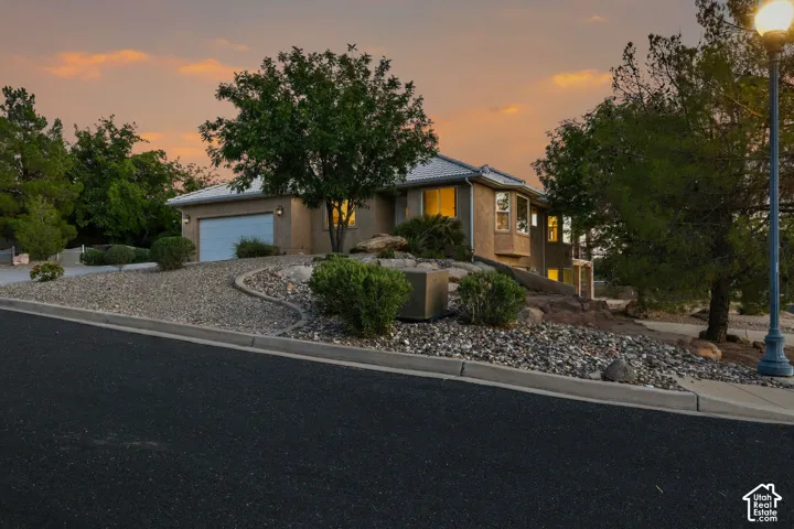 Stucco exterior with a garage door, mature trees, and a bay window
