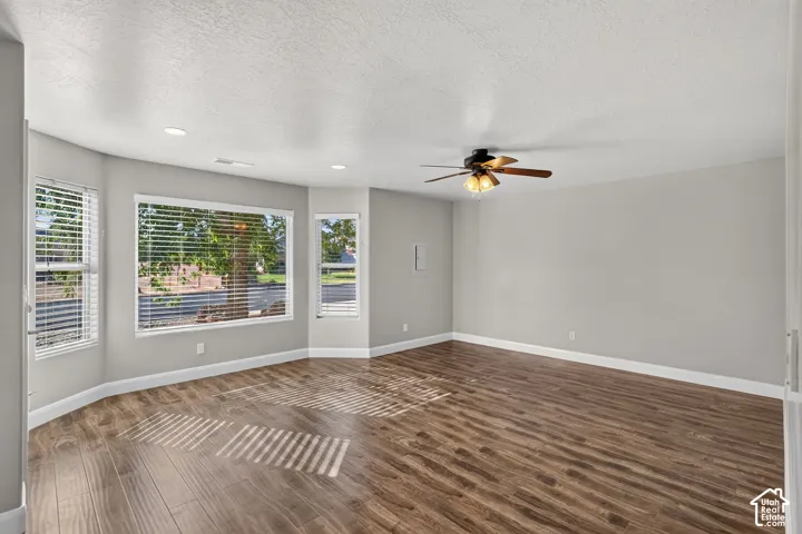 Spacious room featuring wood-finish flooring, recessed lighting, and a ceiling fan