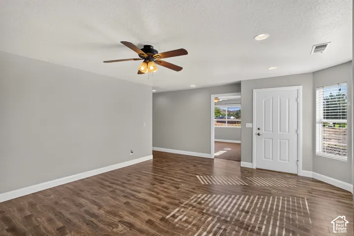 Wood-finish flooring, recessed lighting, ceiling fan light fixture, multi-paneled door, and bay window with blinds