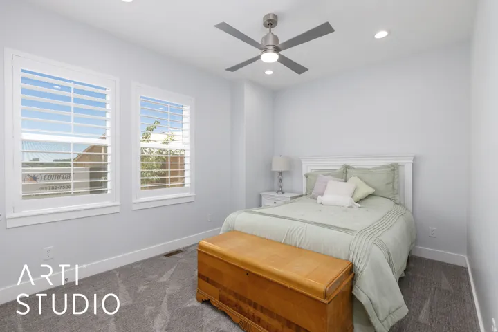 Two windows with white plantation shutters, overhead ceiling fan with lighting, recessed ceiling lighting, and gray carpet