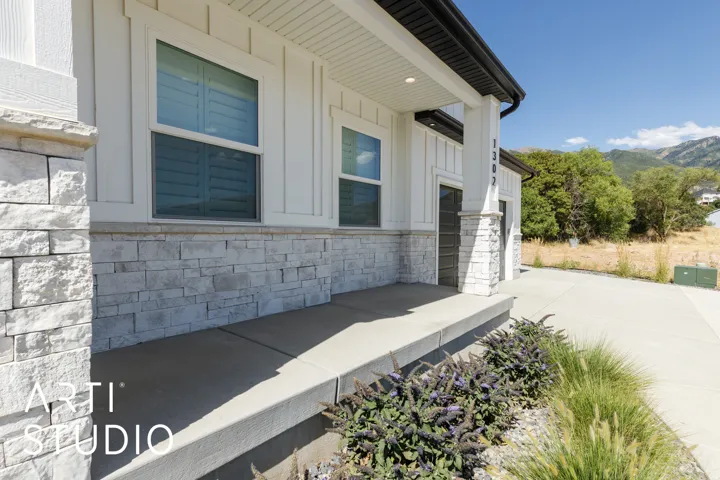 Exterior featuring board and batten siding, stone facade, covered front porch, and concrete driveway