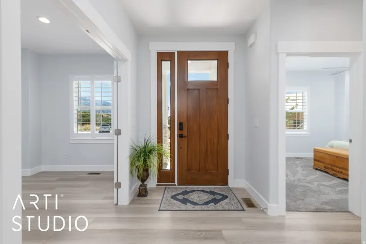 Entryway featuring a wood-finish door with sidelight, light wood-finish flooring, and bright white trim