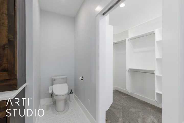 Powder room with hexagon tile flooring and a built-in toilet, featuring an adjacent closet with built-in shelving and hanging rods