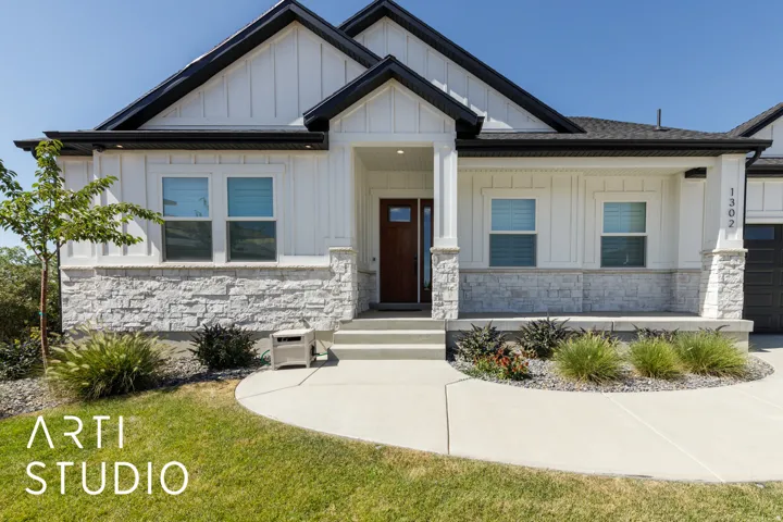 Contemporary exterior featuring vertical siding, stone accents, black-trimmed roofline, covered entry, and a prominent wood-finish front door