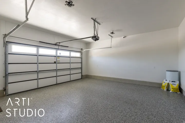 Spacious garage featuring a durable epoxy floor, a garage door with integrated windows, and an automatic garage door opener
