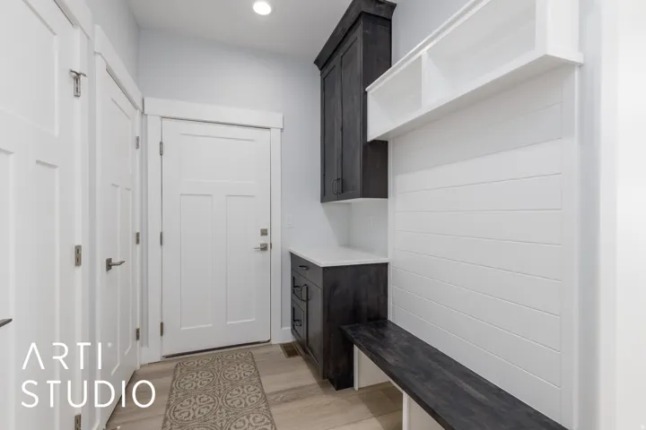 Entryway featuring white shaker doors, recessed lighting, wood-finish flooring, built-in dark wood cabinetry with white countertop, and white shiplap-style paneling with integrated shelving