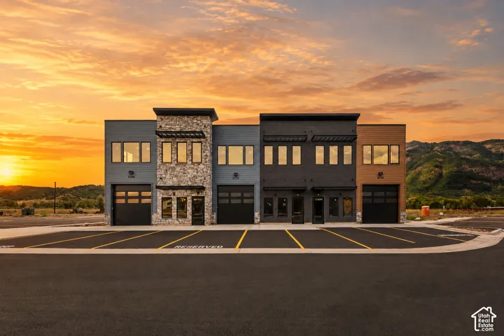Modern multi-unit commercial building featuring mixed material facades, ground-level roll-up doors, and expansive window lines