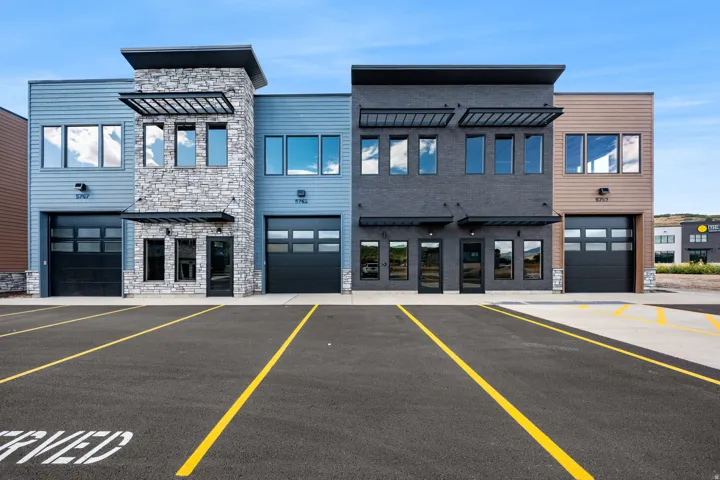 Modern multi-unit commercial building featuring clean-lined facades with mixed materials including stone veneer, fiber cement siding, and brick accents
