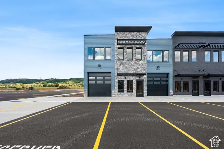 Building exterior featuring horizontal siding, stacked stone accents, multiple large windows, and an overhead garage door