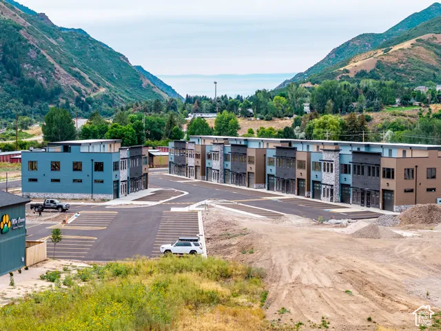 Modern townhomes featuring a multi-tone facade with stone and paneling accents, individual garage doors, and paved parking areas