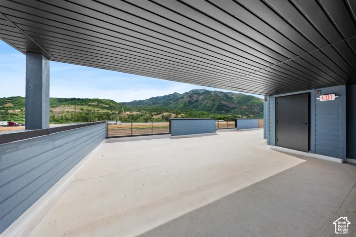 Expansive outdoor terrace featuring concrete flooring, a slatted ceiling, and a metal railing system