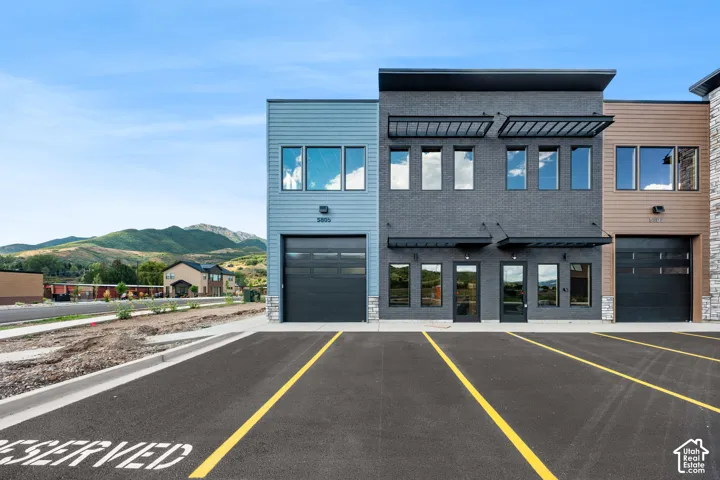 Modern multi-story facade featuring mixed-material construction, multiple garage doors, and individual entryways