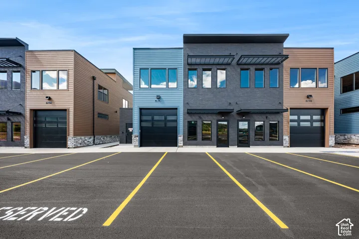 Modern commercial buildings featuring varied siding materials, large windows, and individual garage doors