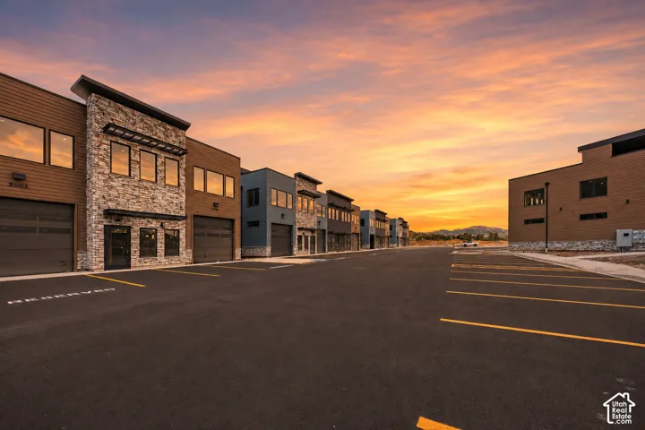 Modern commercial buildings featuring stone and wood-look siding, dark-framed windows, and roll-up garage doors