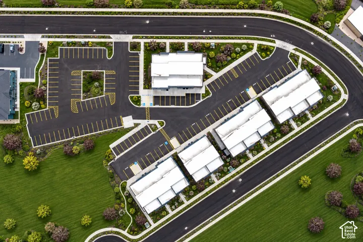 Expansive paved parking areas with marked spaces, multiple building structures with white rooftops, and surrounding manicured green spaces