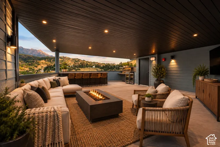 Expansive covered outdoor living area featuring a built-in bar with seating, a fire pit, and recessed lighting