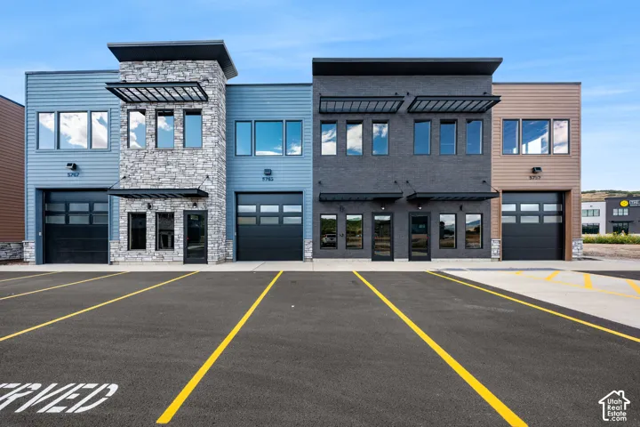 Modern multi-unit commercial building featuring clean-lined facades with mixed materials including stone veneer, fiber cement siding, and brick accents