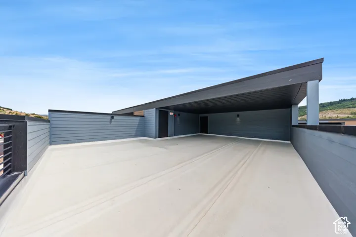 Expansive outdoor patio with a partial covered area, modern railing, and panel siding
