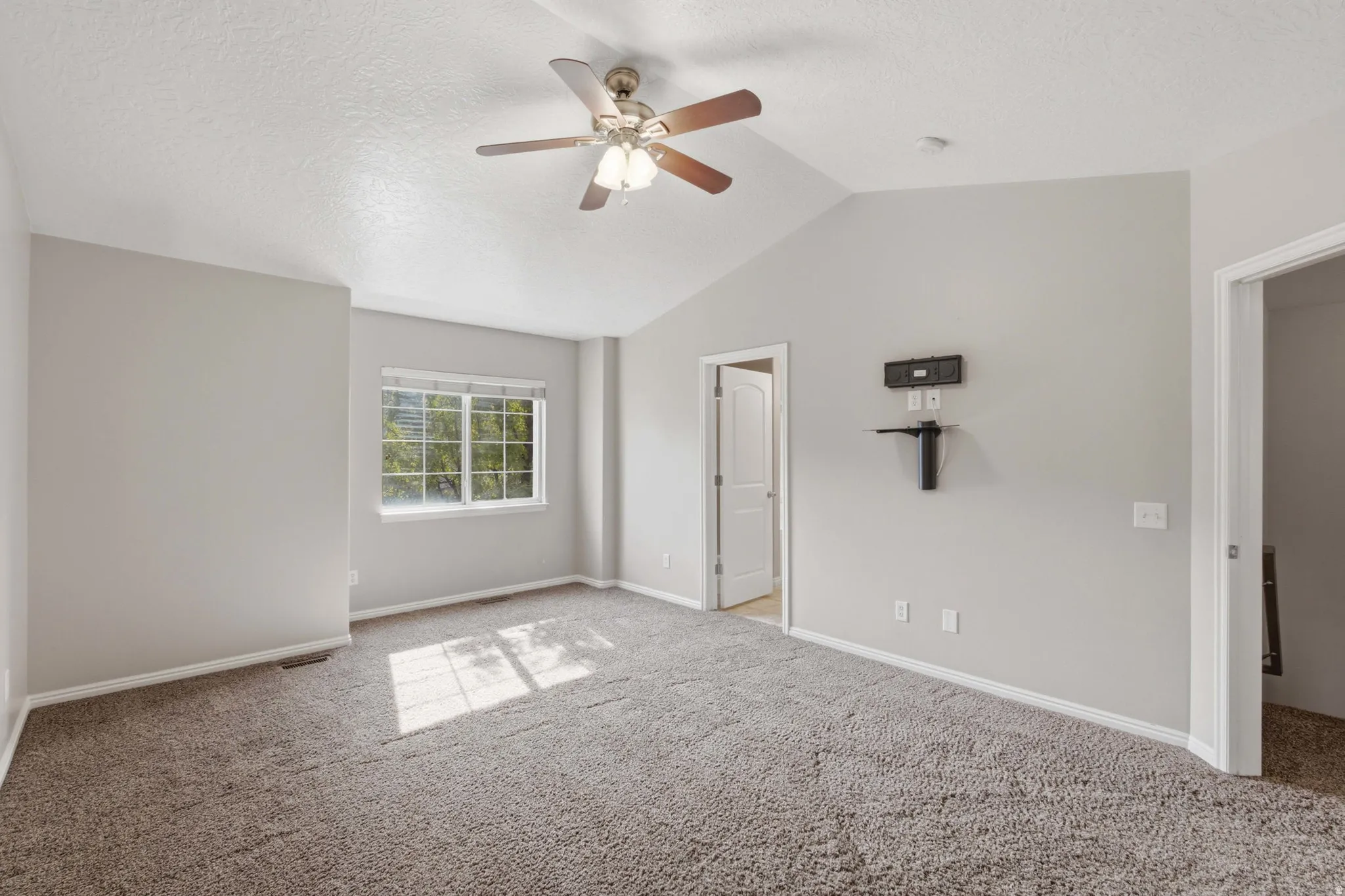 Bright primary bedroom featuring neutral wall finishes, carpeted flooring, ceiling fan with integrated lighting, and abundant natural light from dual windows
