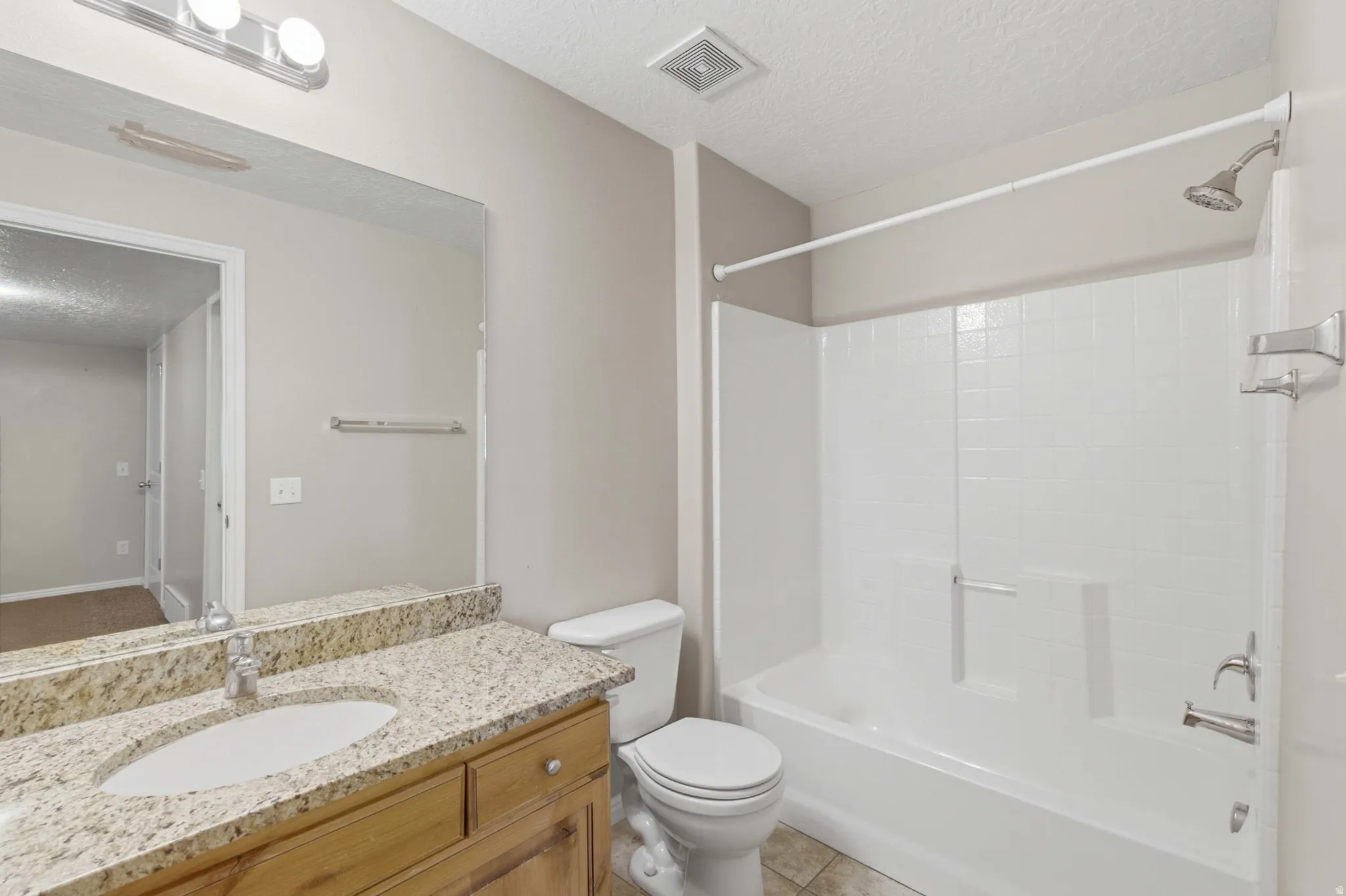 Spa-inspired bathroom featuring a dual-sink vanity with warm wood cabinetry, granite countertops, and polished nickel hardware
