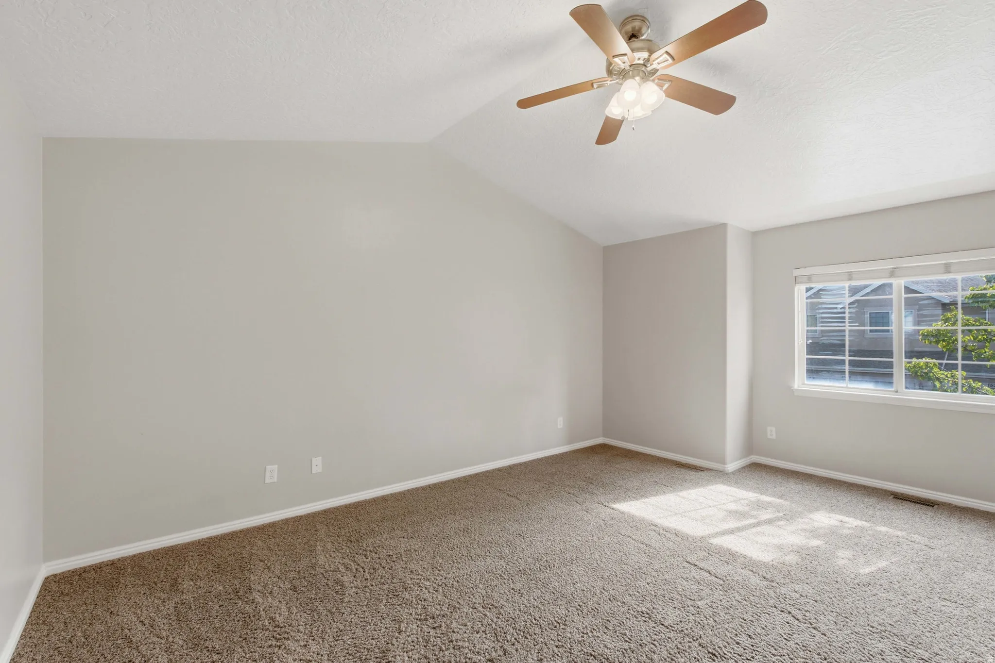 Spacious bedroom with neutral walls, plush carpeting, and abundant natural light from dual windows