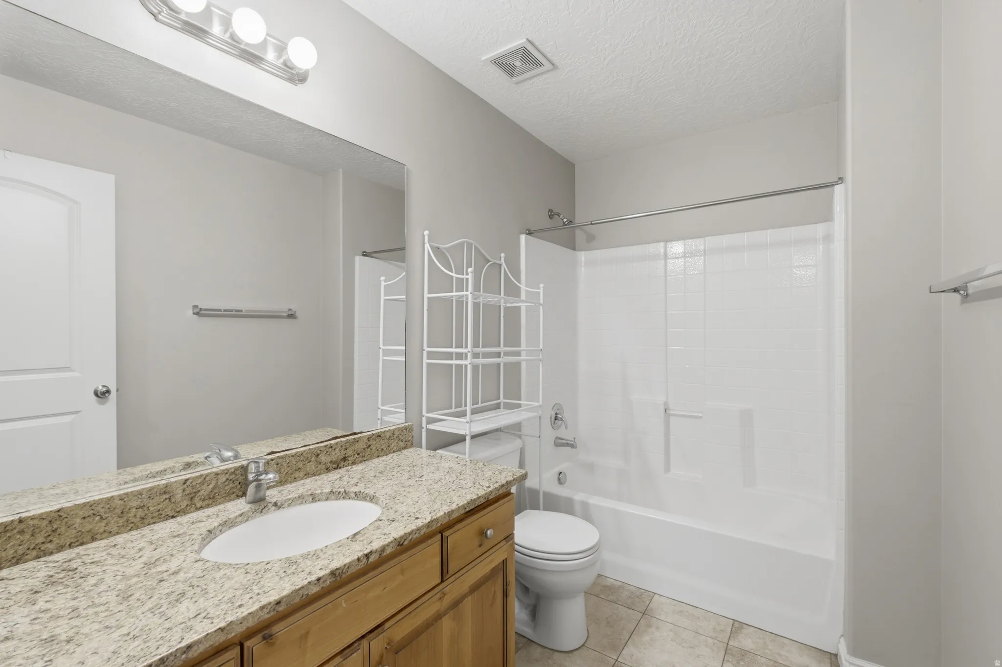 Spa-inspired bathroom featuring a wood-finish vanity with dual sinks, granite countertop, and brushed nickel hardware
