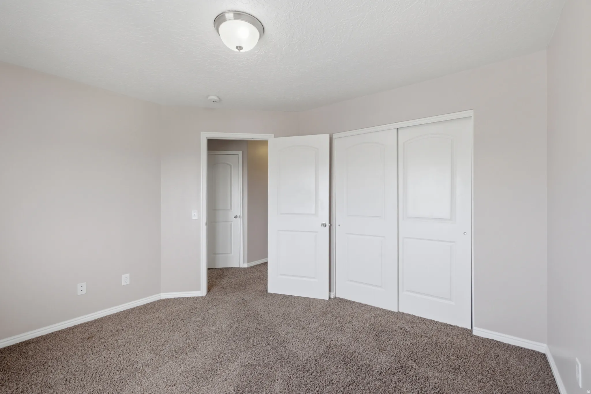 Spacious bedroom with plush carpeting, abundant natural light, and generous closet storage featuring multiple white panel doors