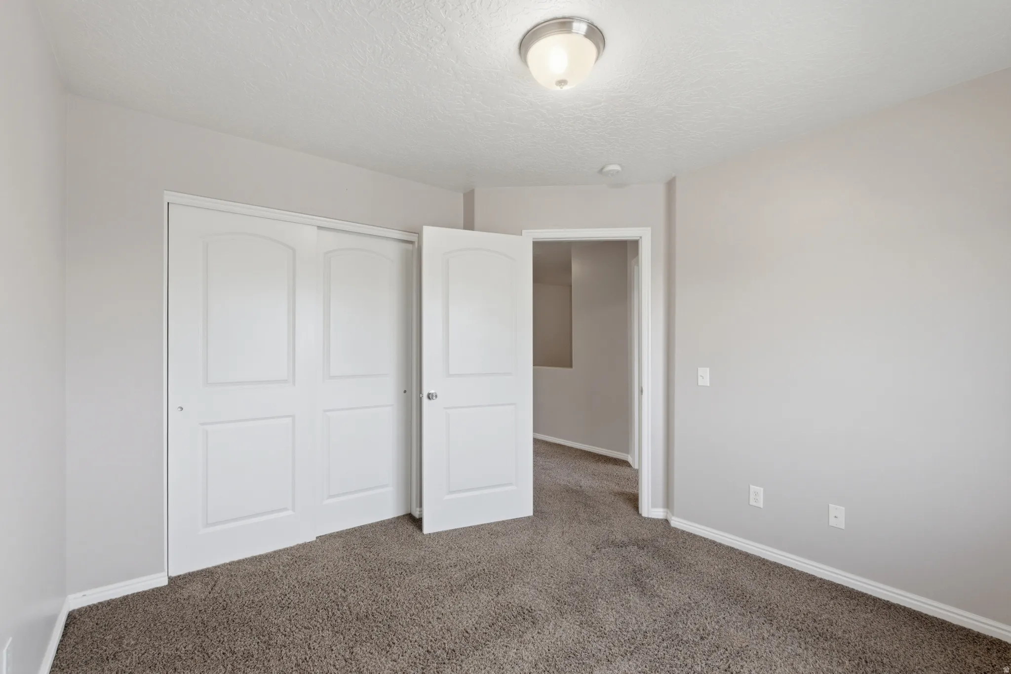 Bright bedroom featuring dual closets with white six-panel doors, neutral carpeting, and ample natural light from recessed ceiling fixtures