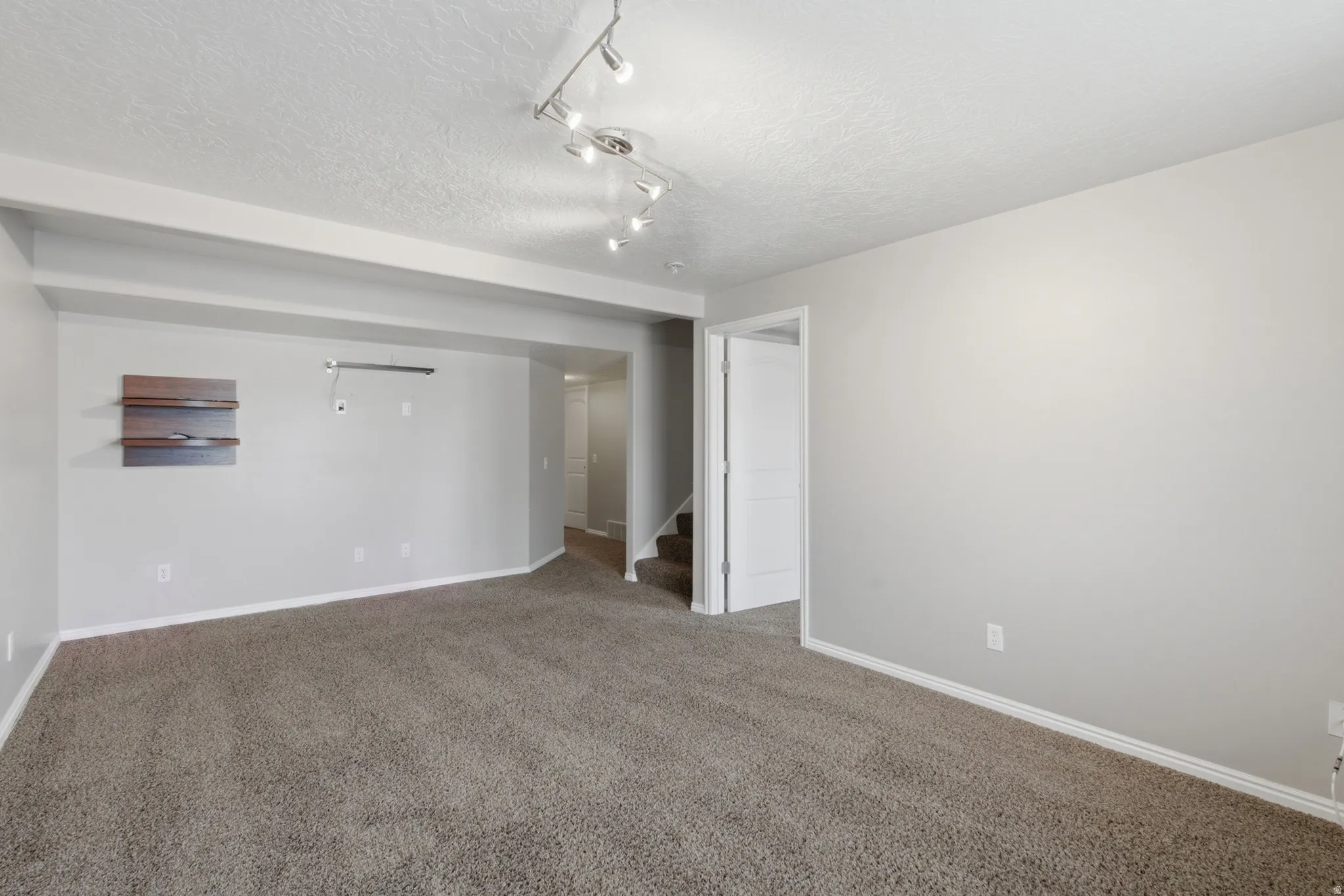 Spacious open-concept living area featuring neutral carpeting, recessed lighting, and track lighting fixtures