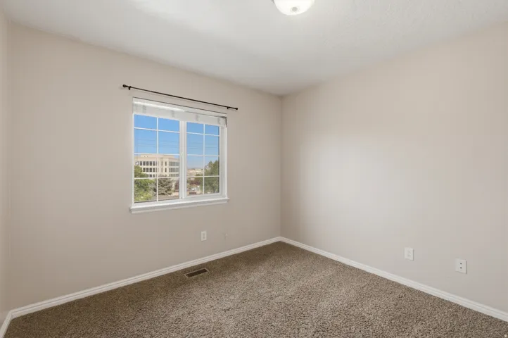Bright, light-filled bedroom with expansive window featuring multiple panes and contemporary frame, neutral wall finishes, and plush carpeting throughout