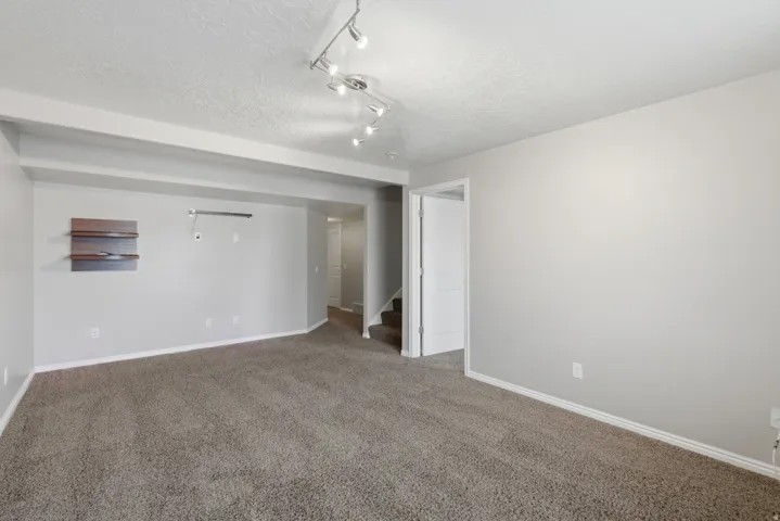 Spacious open-concept living area featuring neutral carpeting, recessed lighting, and track lighting fixtures