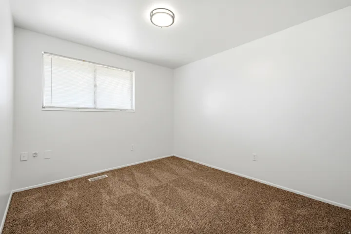 Neutral wall paint, recessed window with blinds, and flush-mount ceiling light