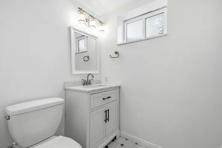 White vanity with a stone countertop, an undermount sink, and a brushed nickel faucet