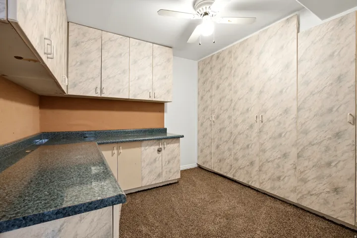 Extensive built-in cabinetry with patterned finishes, coordinating countertops, and ceiling fan