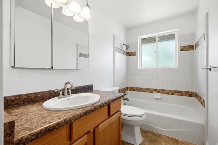 Vanity with a wood-finish cabinet and speckled countertop