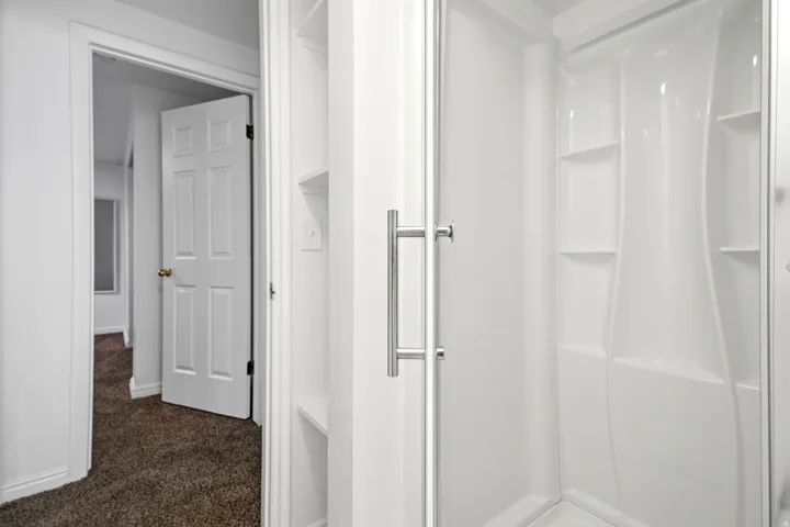 Integrated shower stall with built-in shelving and clear glass enclosure